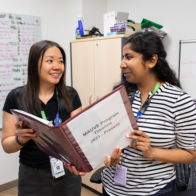 Two MAUVE volunteers holding a file looking at each other