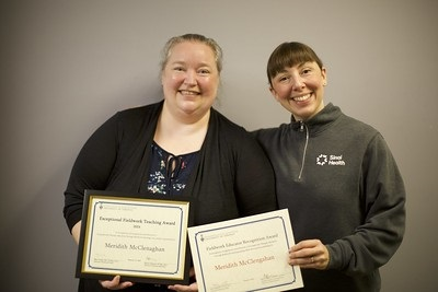 Two people standing looking at the camera smiling, they are each holding a certificate.