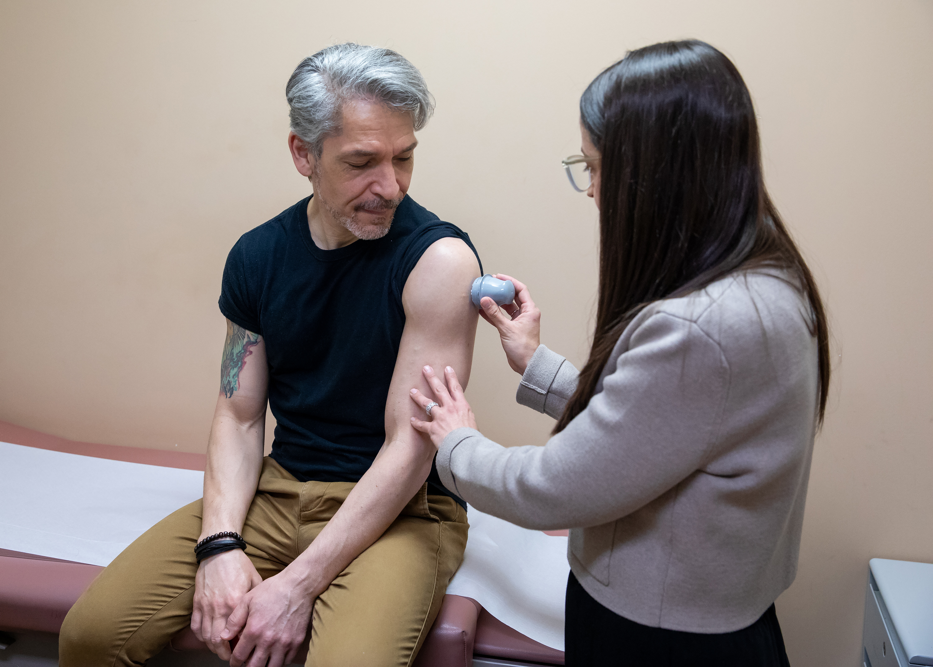 a female physician inserting a glucose monitor under the skin on a patient's upper arm