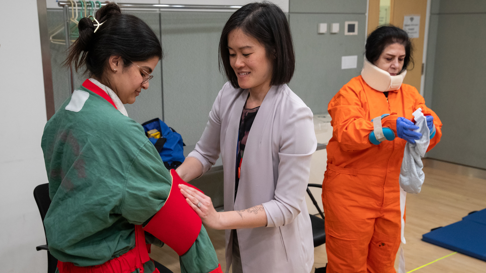 Alt text: Sinai Health employees donning a coverall-type suit that simulates some effects of aging