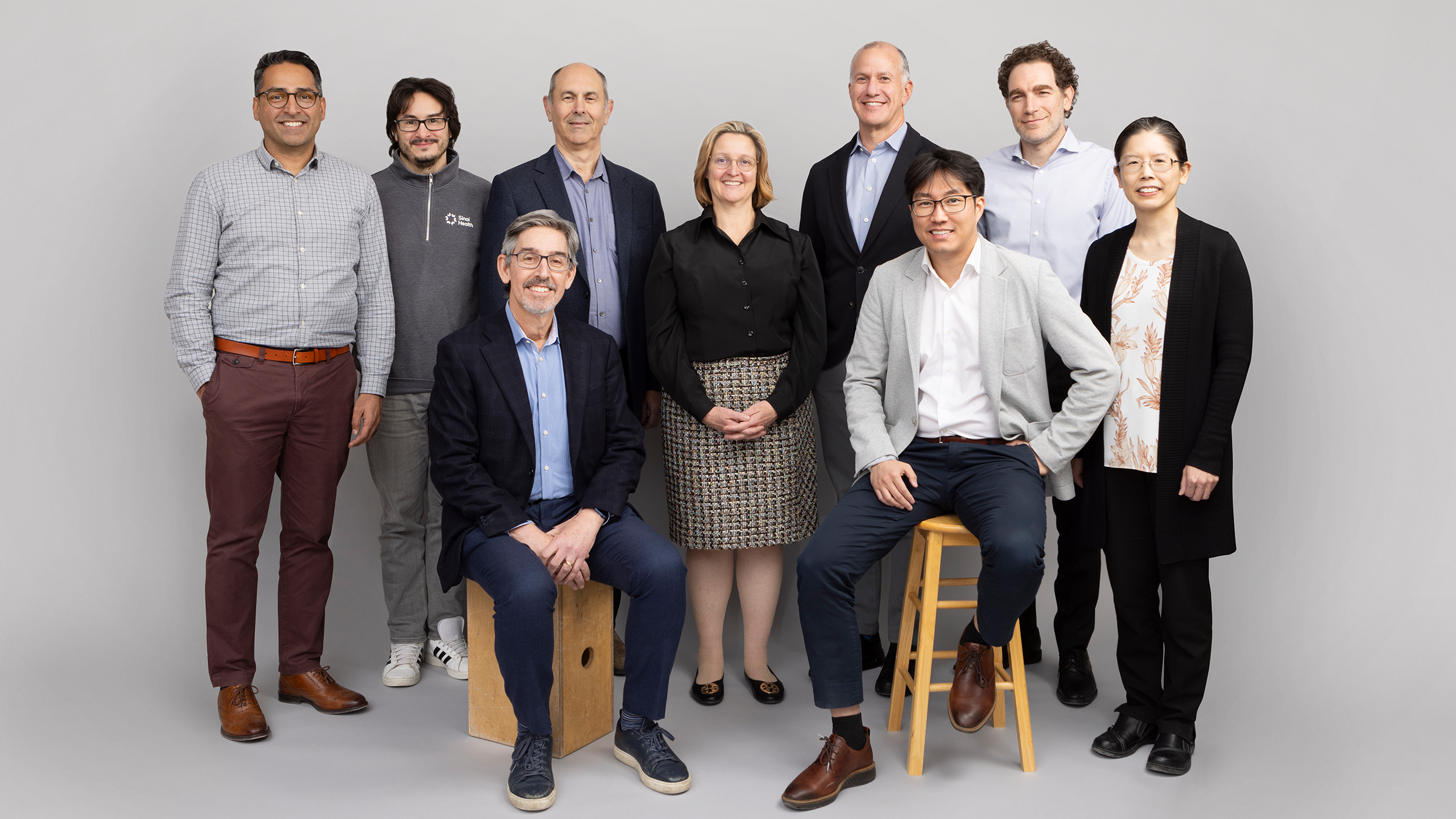 Group of professionals posing in front of a grey background.