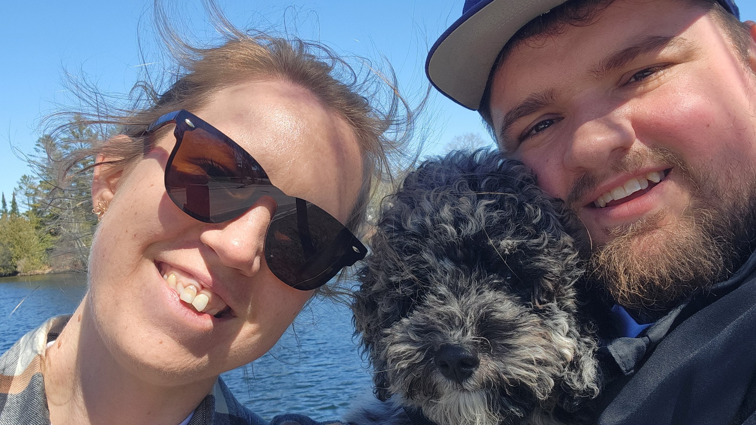 woman and man with dog stand by a lake