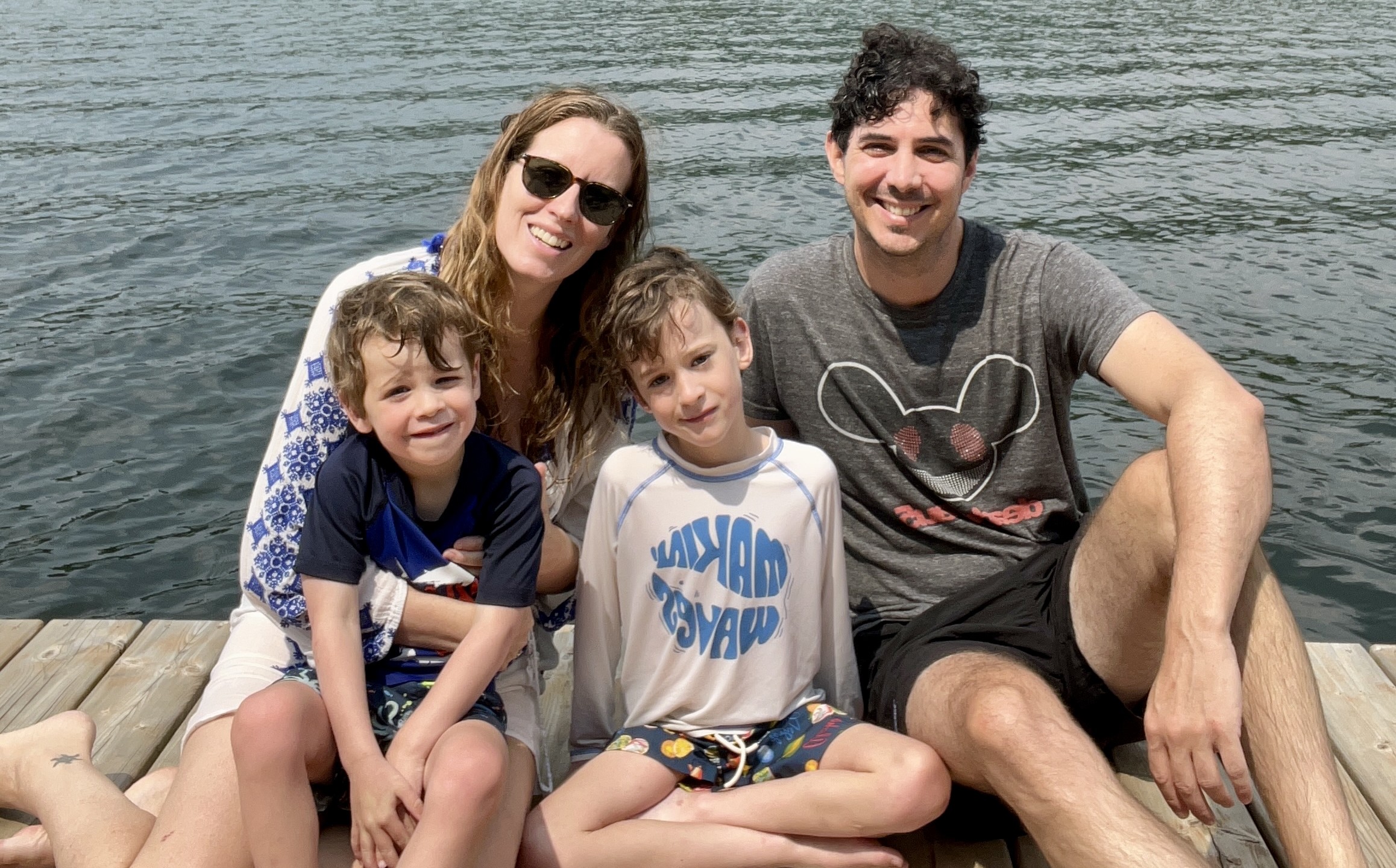 family of four sitting on a dock beside the water