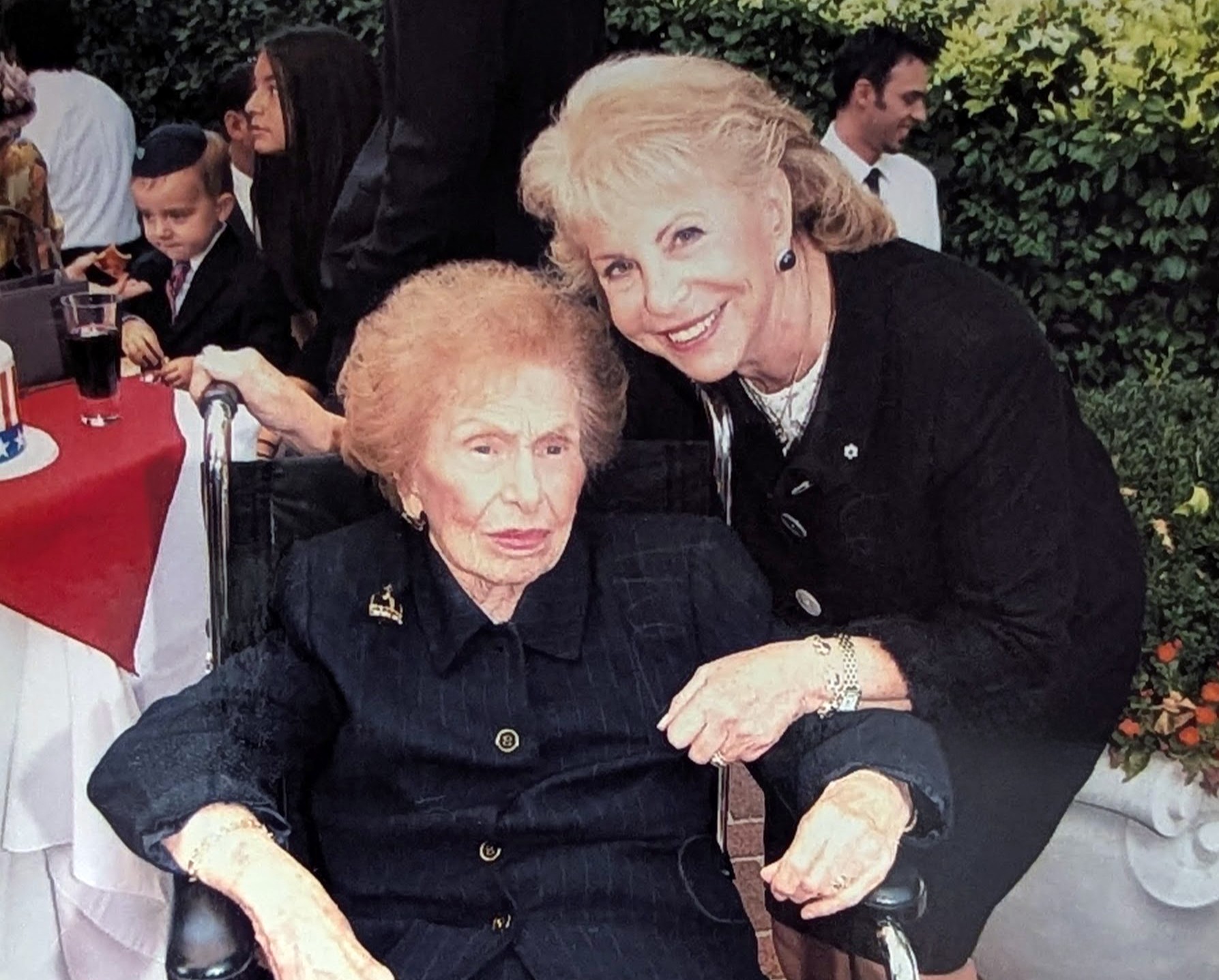 One woman stands with another woman who is in a wheelchair