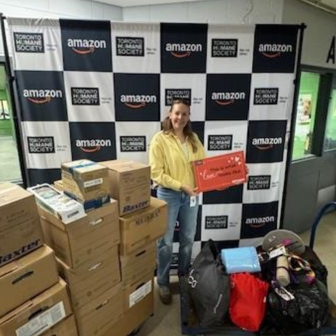 a Woman stands behind a cart stacked with boxes to be donated to the Toronto Humane Society