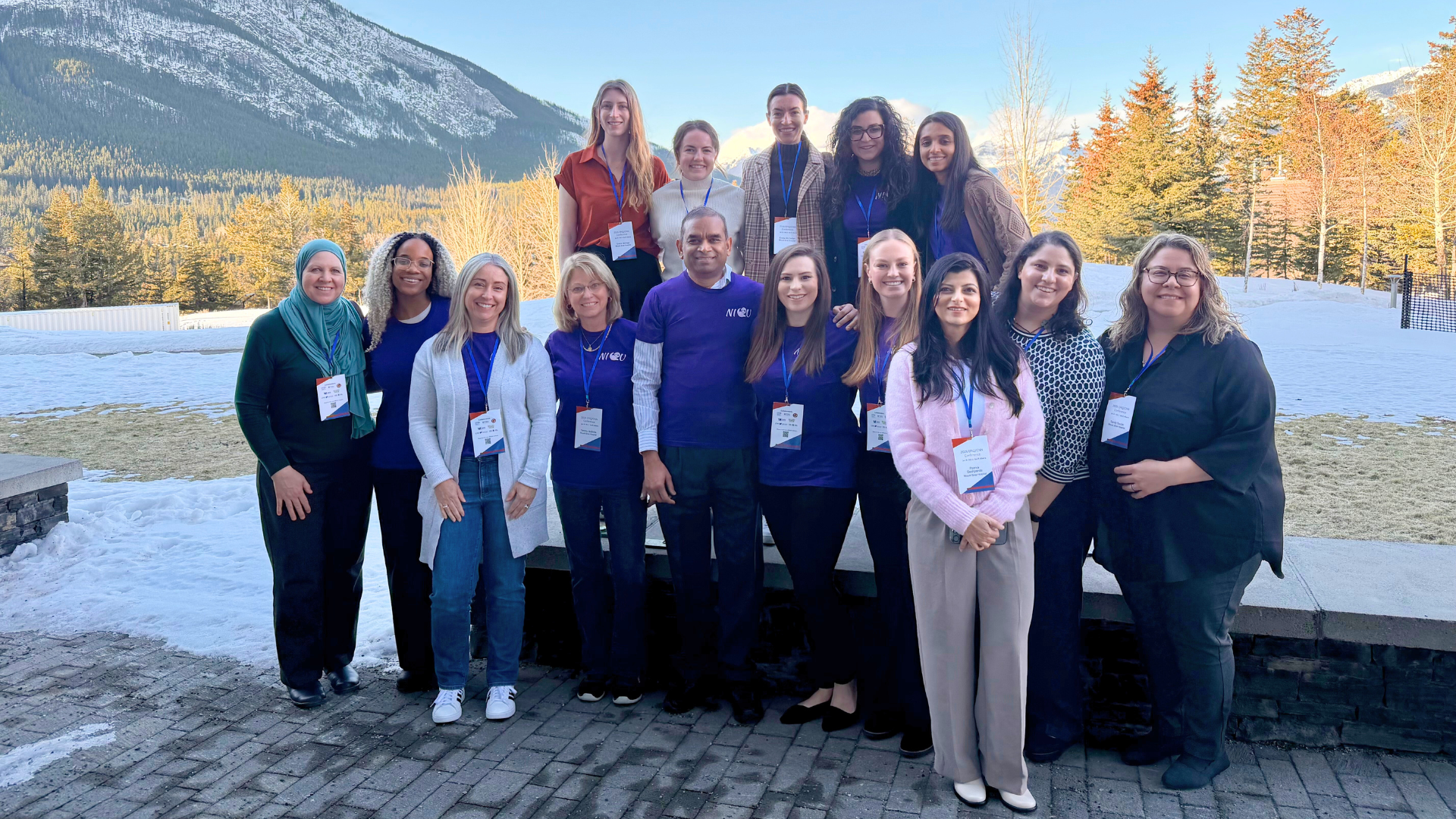 A group of health care workers standing looking at the camera, smiling, they are outside with a green, hilled landscape in the background