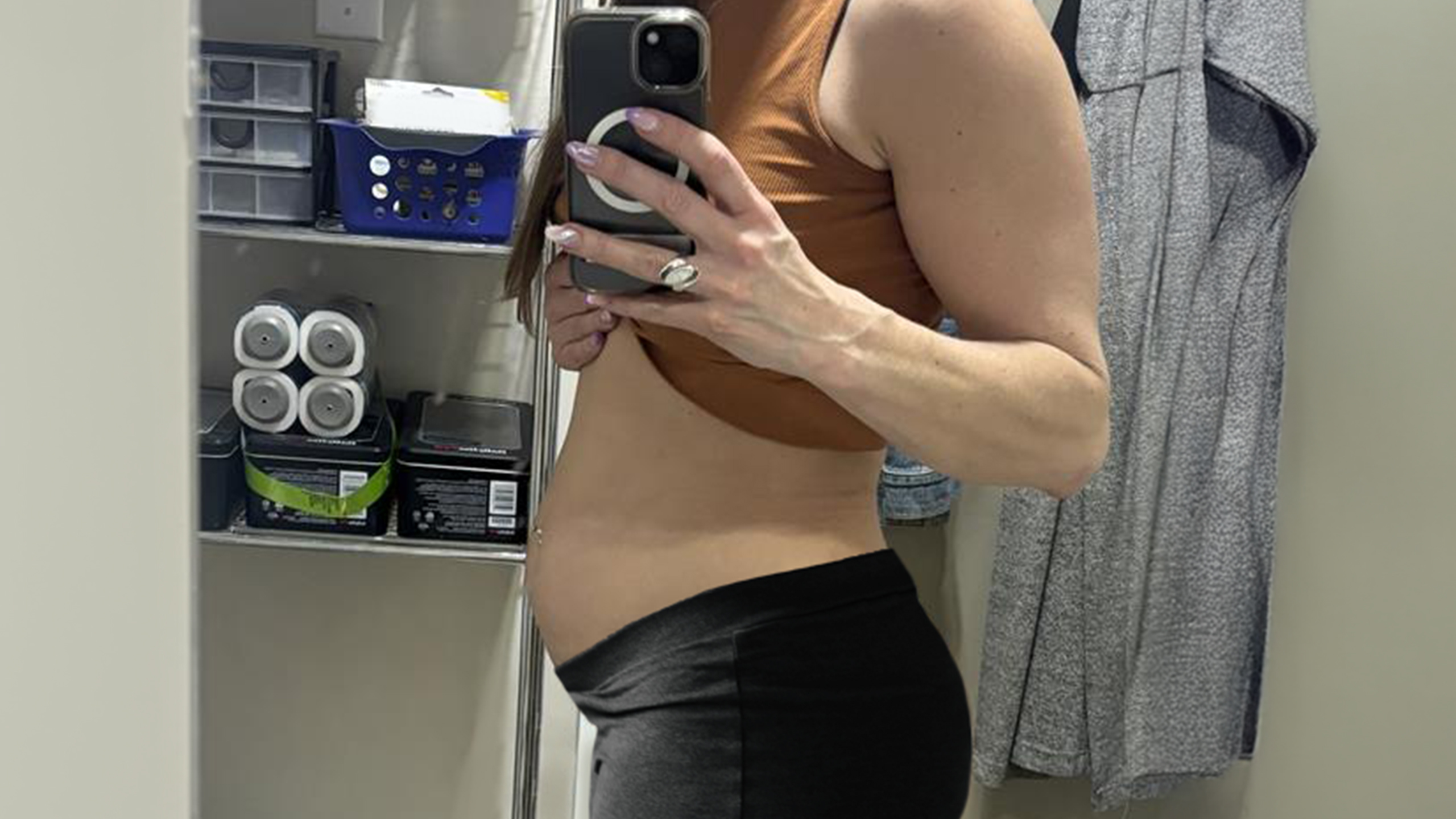 woman with swollen abdomen stands in bathroom