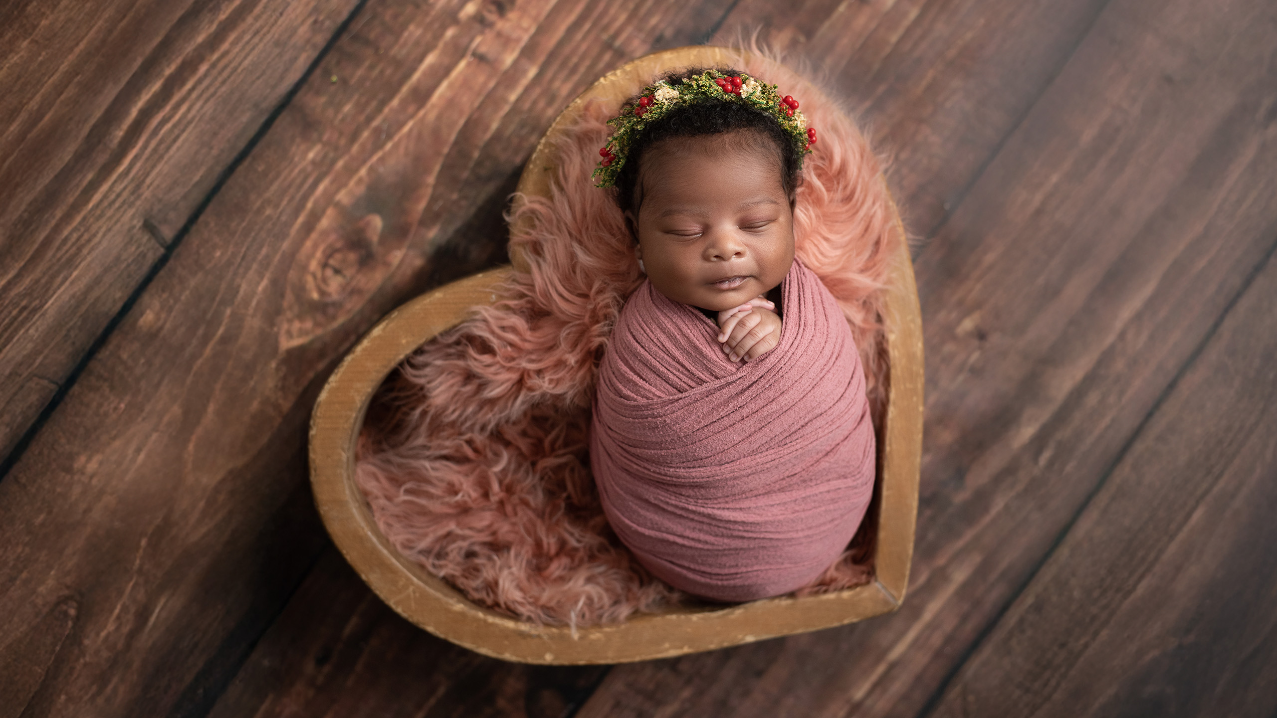 small baby wrapped in pink, laying in a heart basket