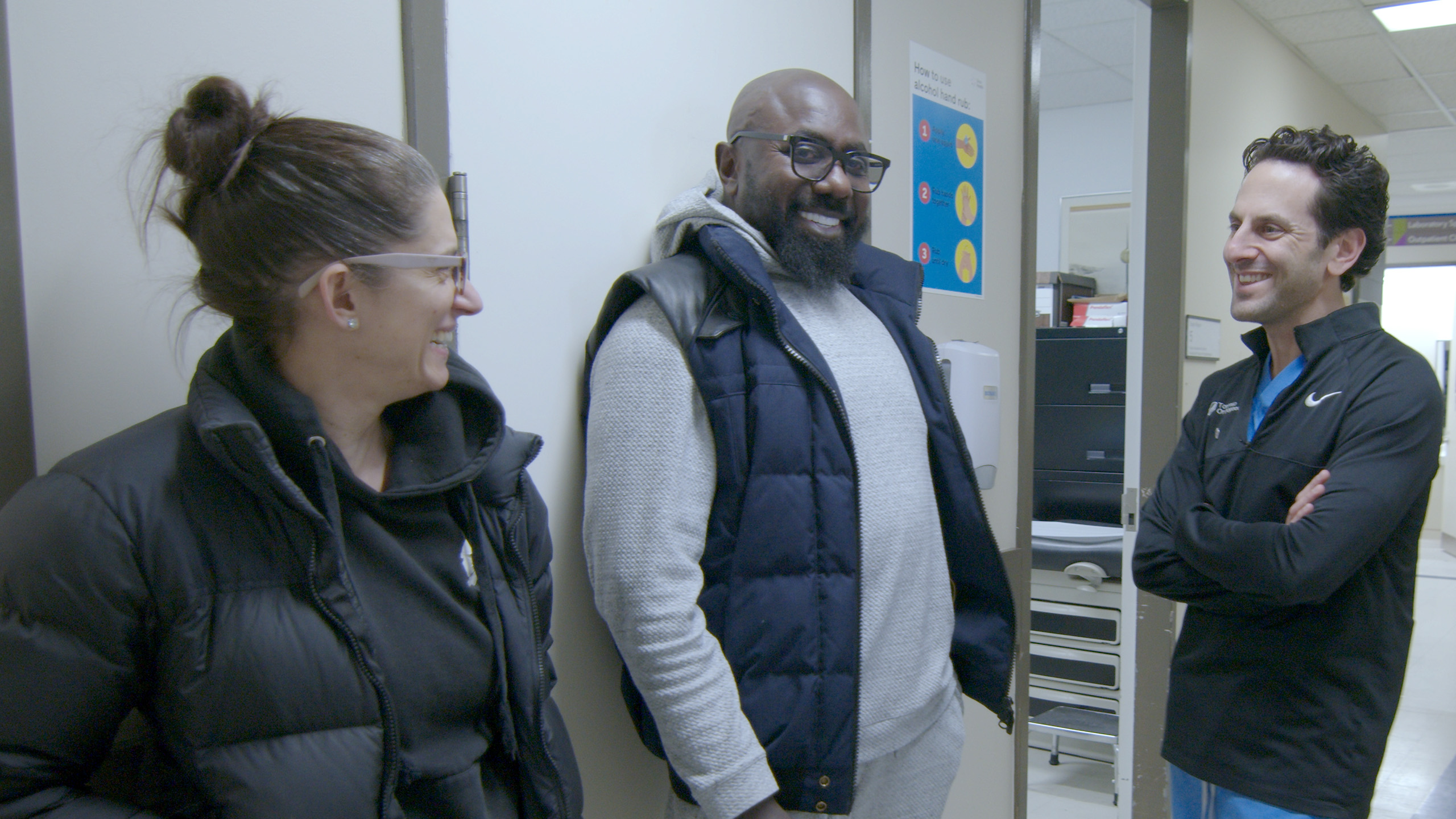 three people stand in hospital hallway