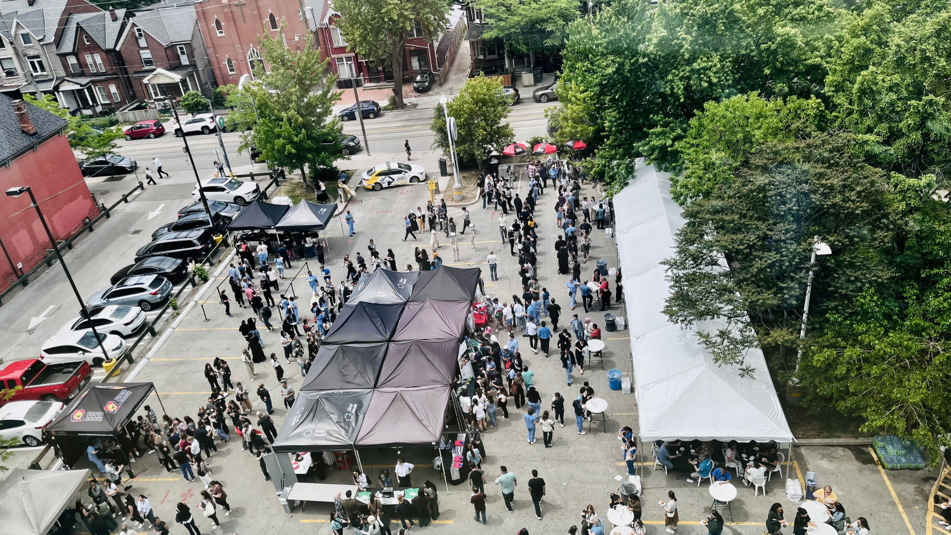 A bird's eye view of the People Appreciation BBQ showing crowds of Sinai Health people at the event. There are tables and tents set up in a parking lot.