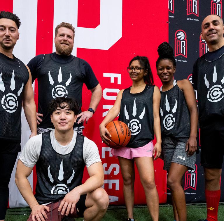 Group of young adults wearing basketball jerseys looking at the camera