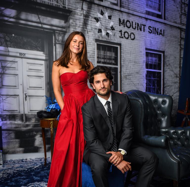 Man and woman posing in front of building backdrop