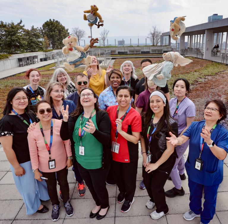 Group standing outside throwing teddy bears into the air