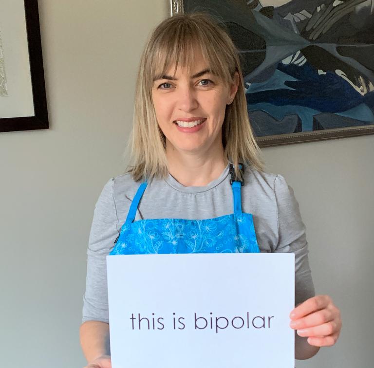 image of woman holding a sign that says 'this is bipolar'