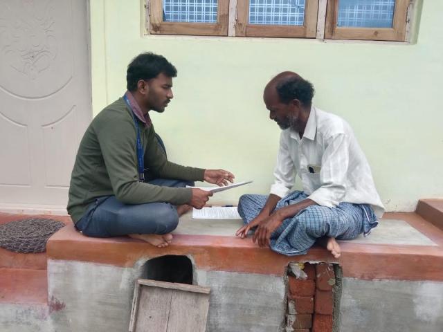 Two Indian men sitting crosslegged and speaking