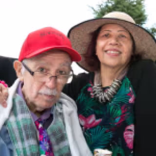 Older man seated with a woman's arm on shoulder