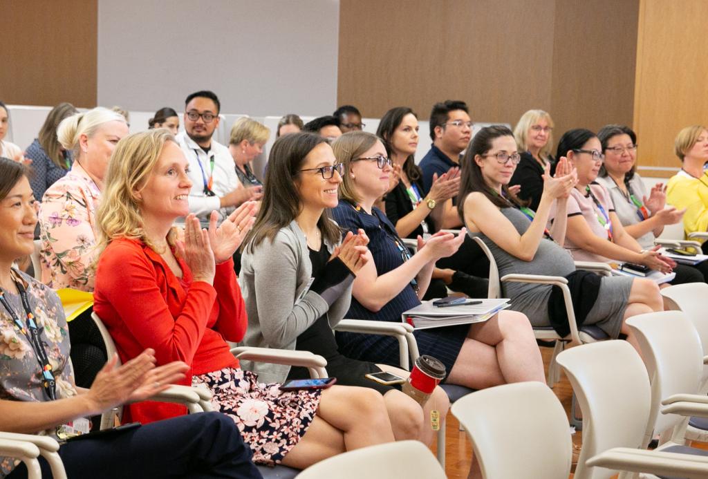 A group of people sits in an auditorium and applauds.