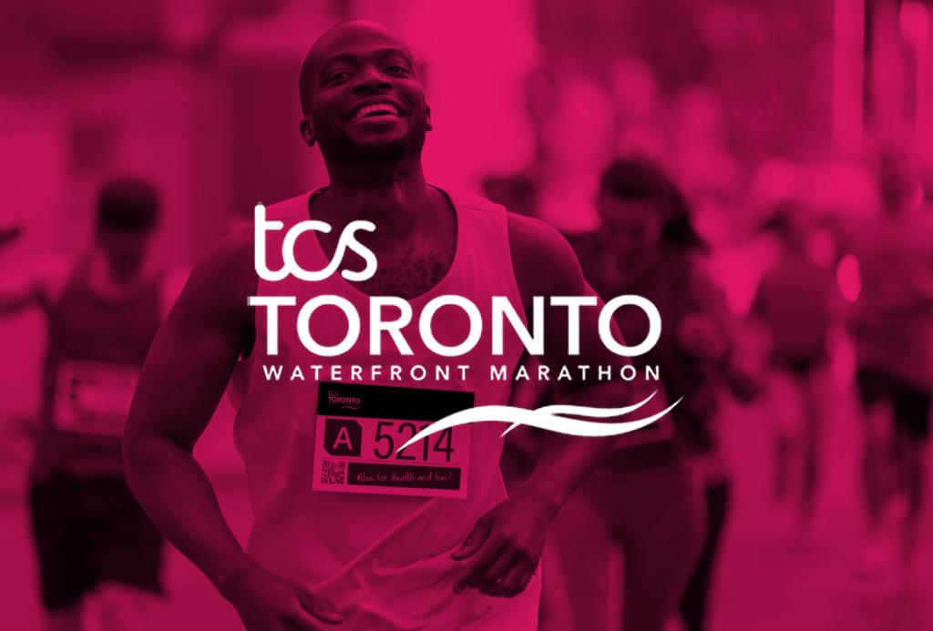 A man smiling while running in a marathon with the white logo that says TCS Toronto Waterfront Marathon