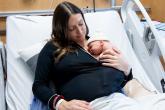 A mother holding her newborn baby in a hospital bed