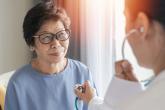 A health care provider uses a stethoscope to listen to an elderly woman's heartbeat