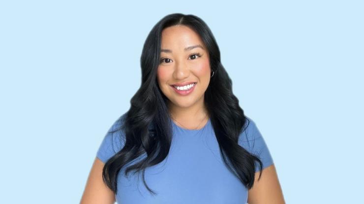 Jennifer Nham, smiling, wearing a blue t-shirt, in front of a light blue background
