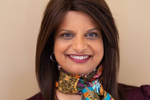 A smiling woman with long hair wearing a colourful scarf.