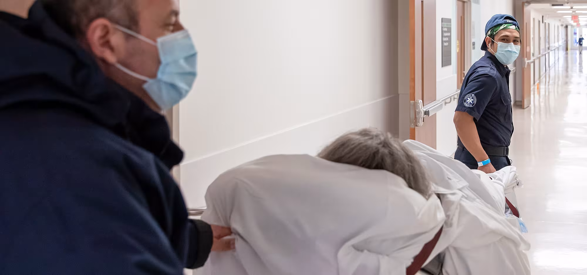 Two people transport a patient down a hallway at Bridgepoint Active Healthcare.