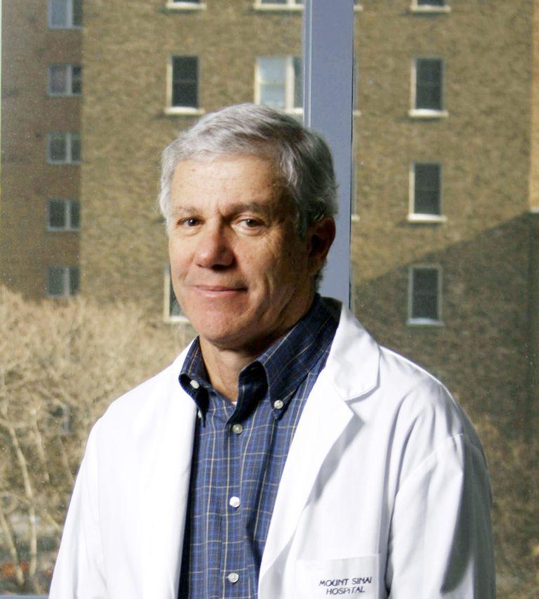 A man in a lab coat with a building in background