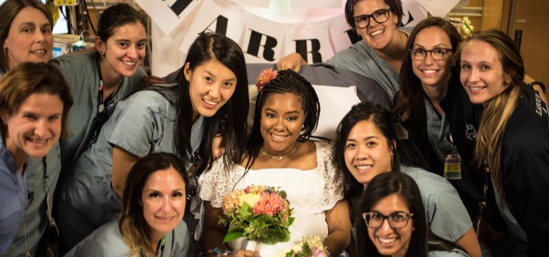 Nurses with patient in wedding dress and bouquet of flowers.