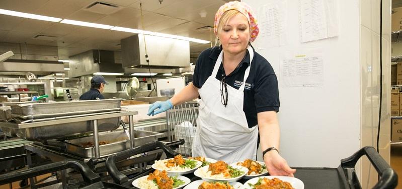 Jessica Godin, Manager, Patient Food Services, giving out plates of food in the Mount Sinai kitchen.