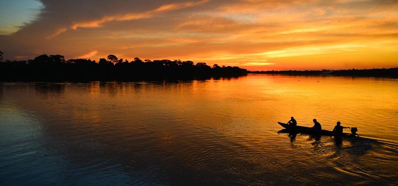 Group canoeing across a late at sunset.