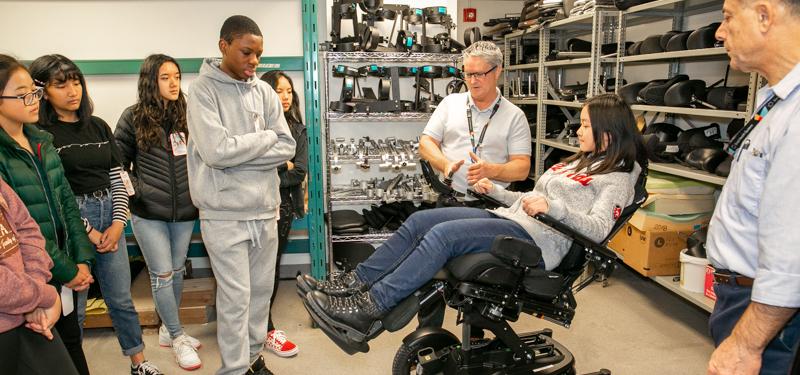 Children examining motorized chair with Sinai Health employees.