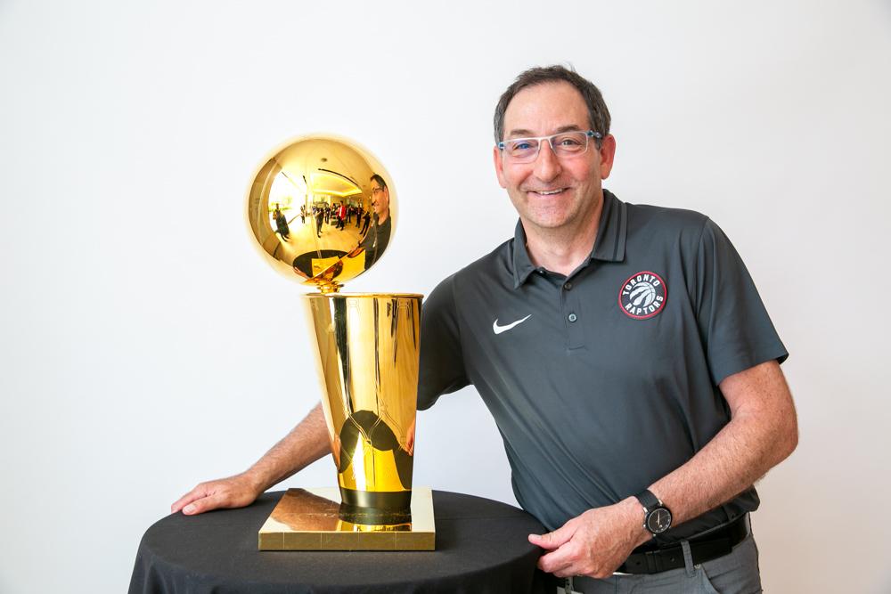 Dr. Howard Petroff posing next to the Larry O'Brien NBA Championship Trophy