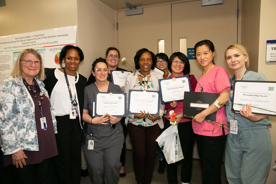A group of nurses stand holding award certificates
