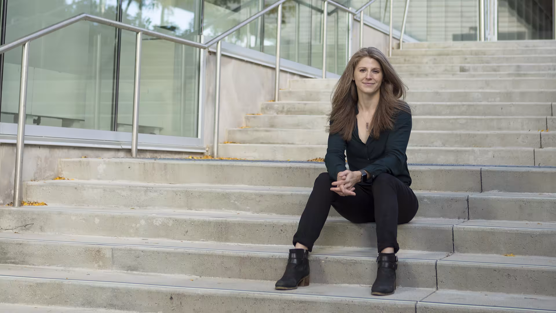 Woman sitting on the steps outside a glass-walled building
