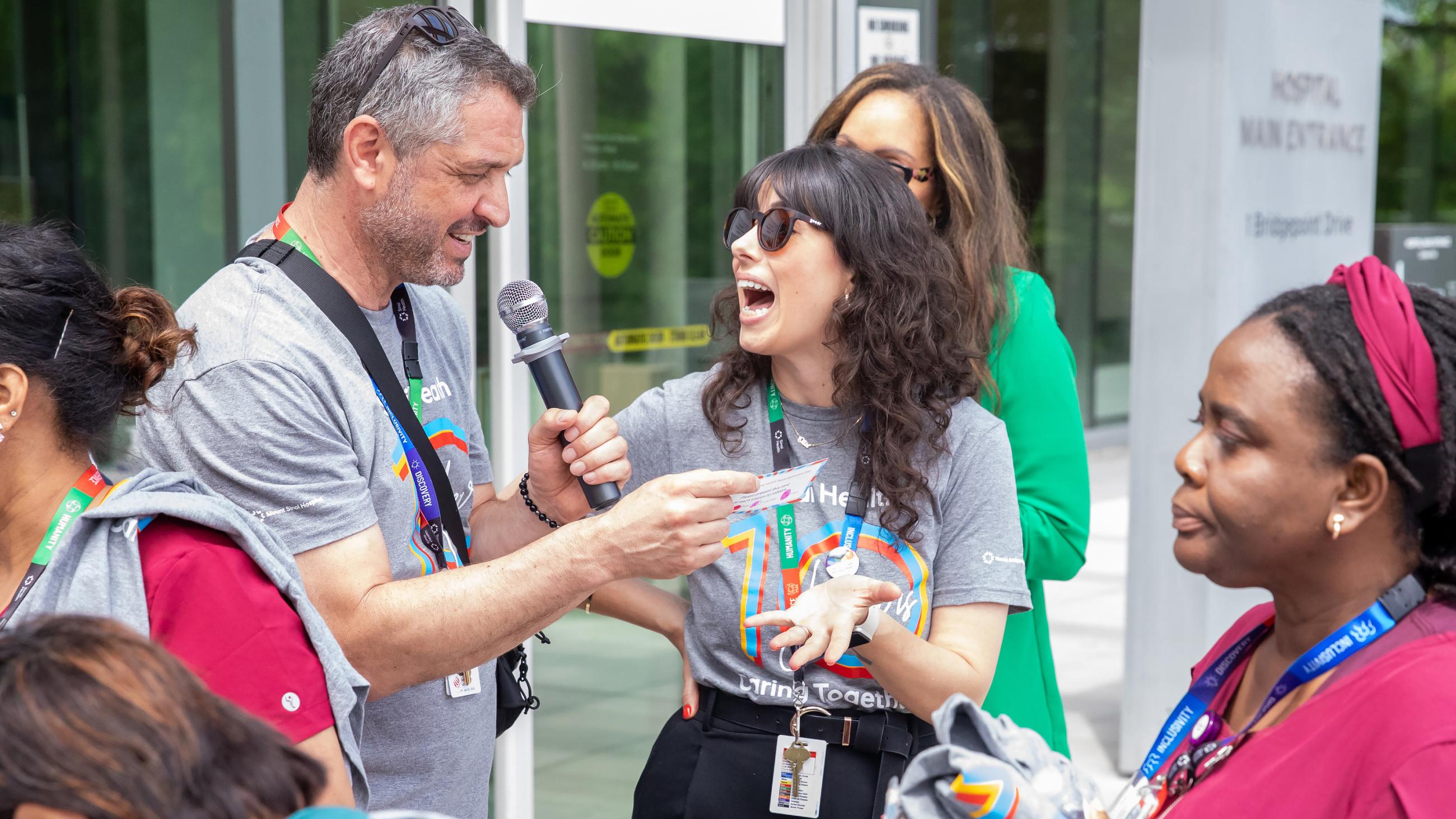 A hospital worker reacting in surprise to an emcee announcing the winner of a prize.