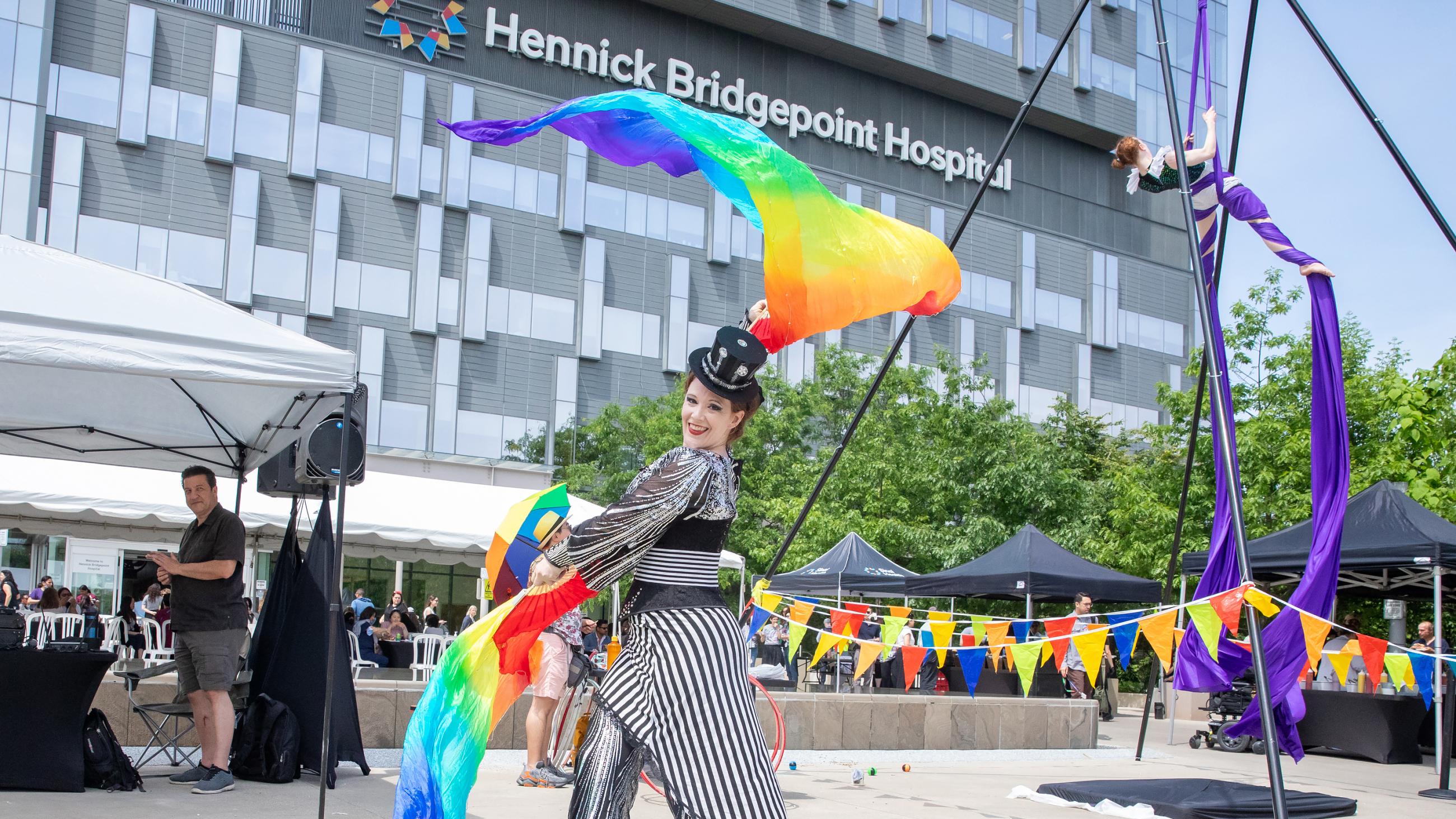 A circus performer entertaining guests by waving rainbow-coloured flags. 