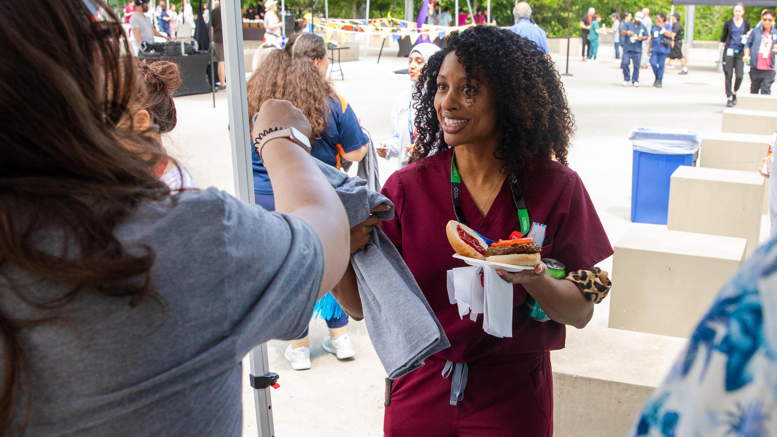 A hospital worker receiving a t-shirt giveaway at the barbeque. 