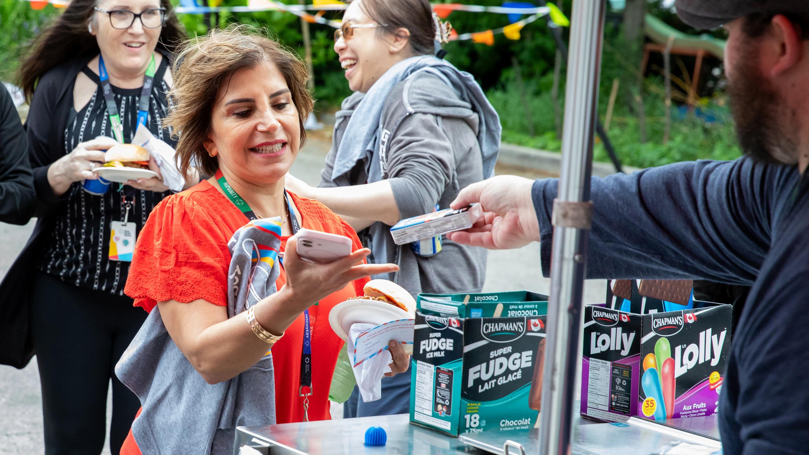 A hospital worker receiving a cold treat at the barbeque. 