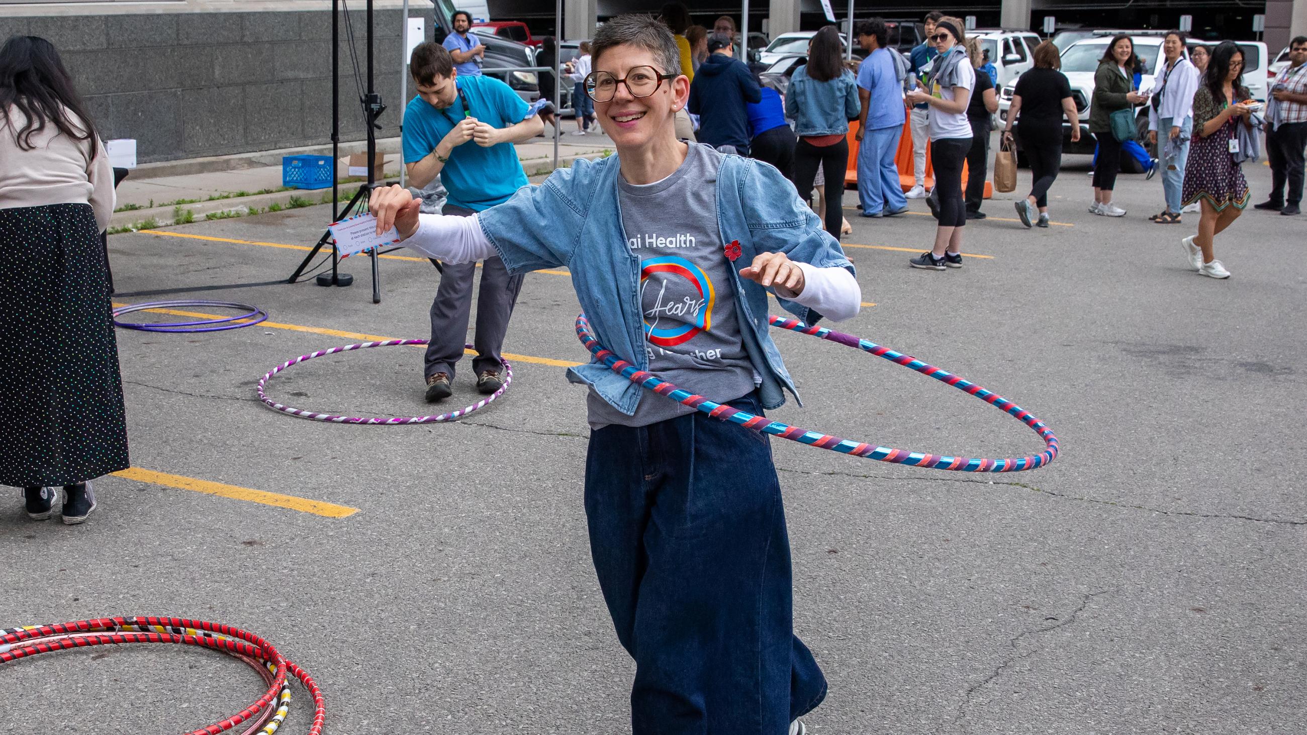A hospital worker spinning a hula hoop around their waist at the barbeque. 
