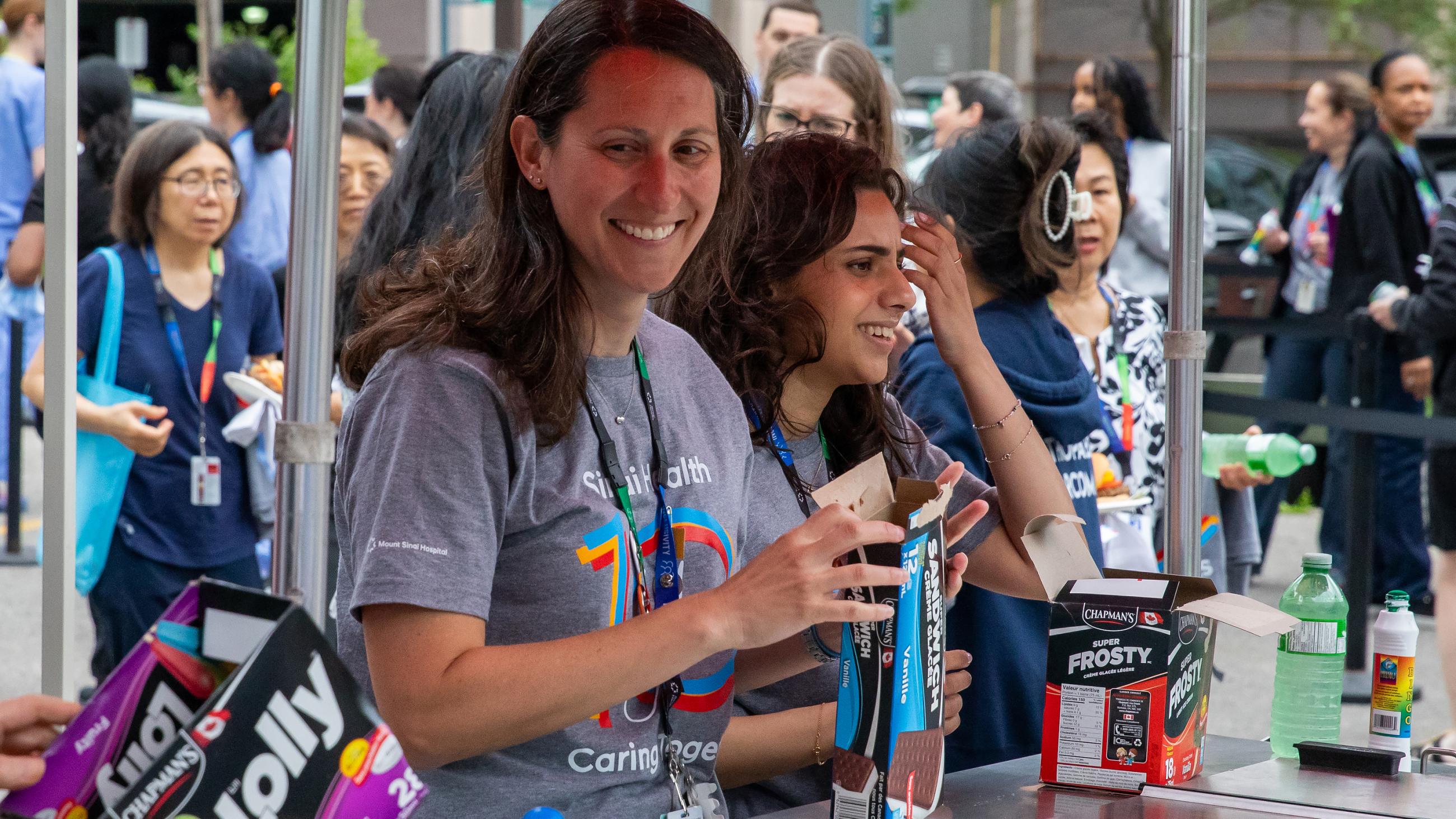 Two hospital workers preparing to hand out cold treats to guests at the barbeque. 