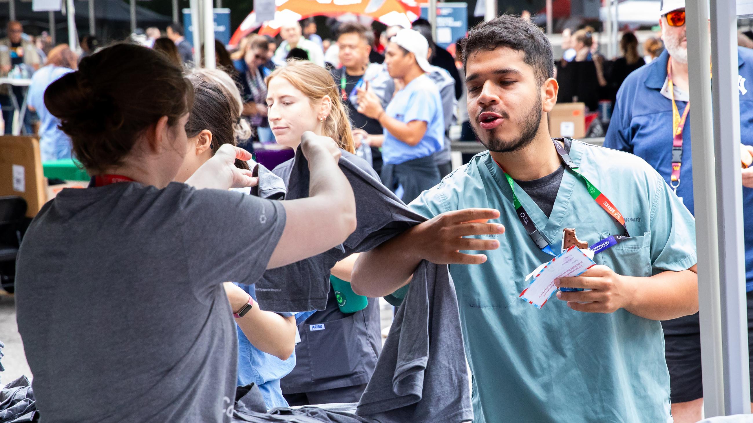 A hospital worker receiving a t-shirt giveaway at the barbeque. 