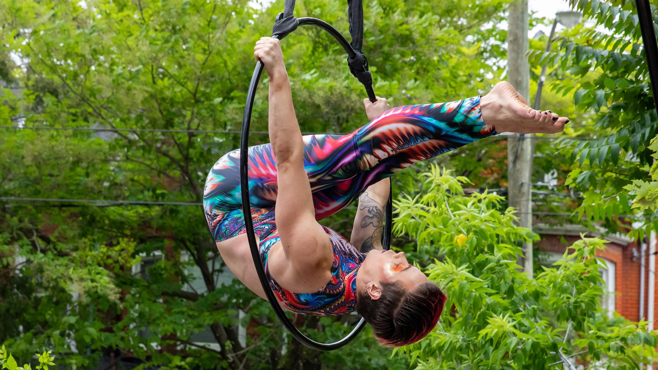 An aerialist hanging in mid-air using a hoop. 