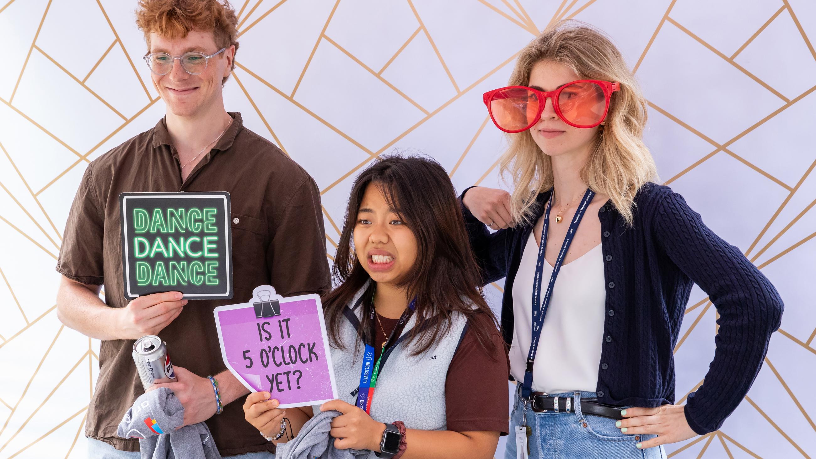 Three colleagues posing together with photo props at the photo booth. 