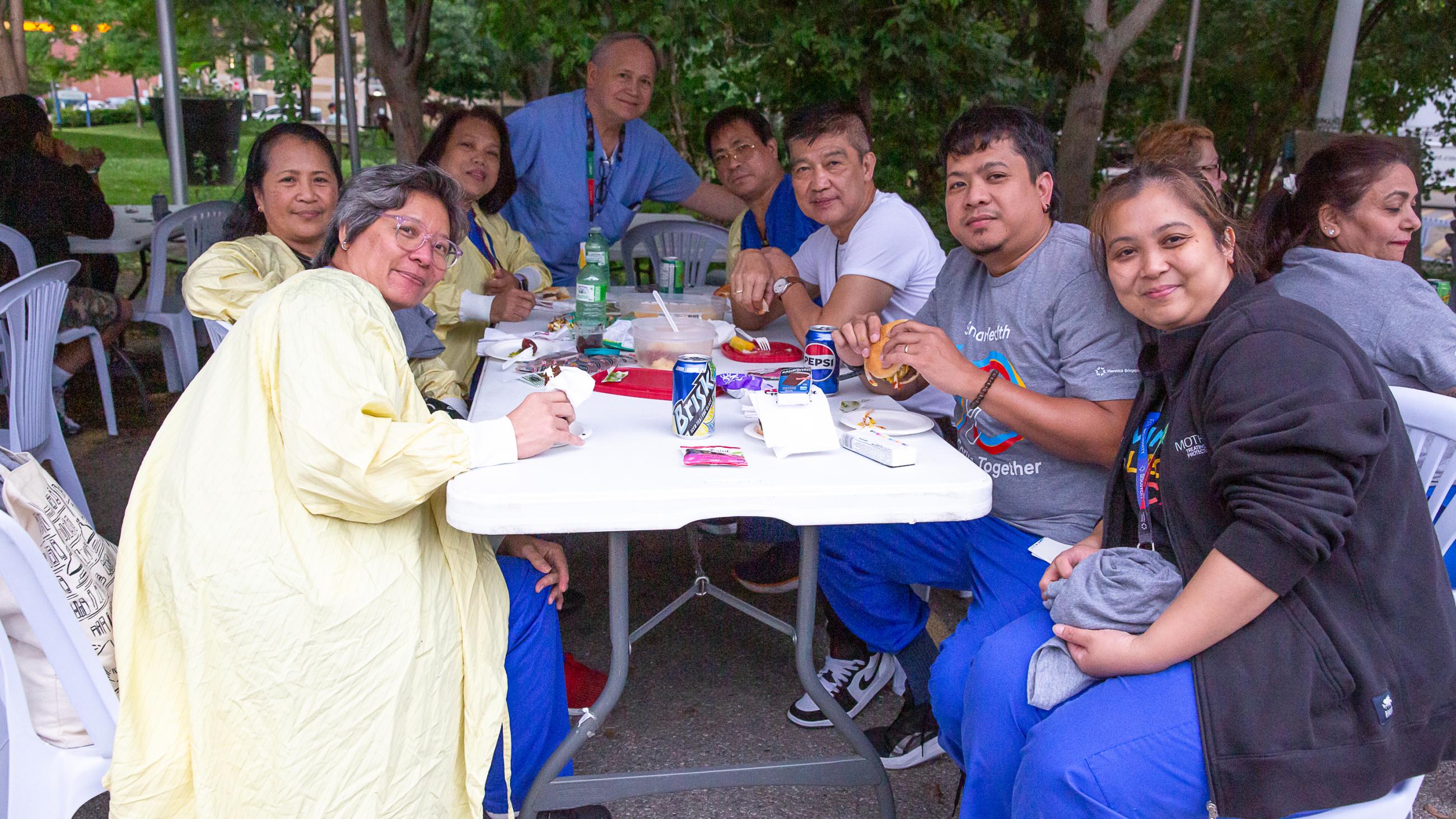 Hospital workers sitting together around a table at the barbeque. 
