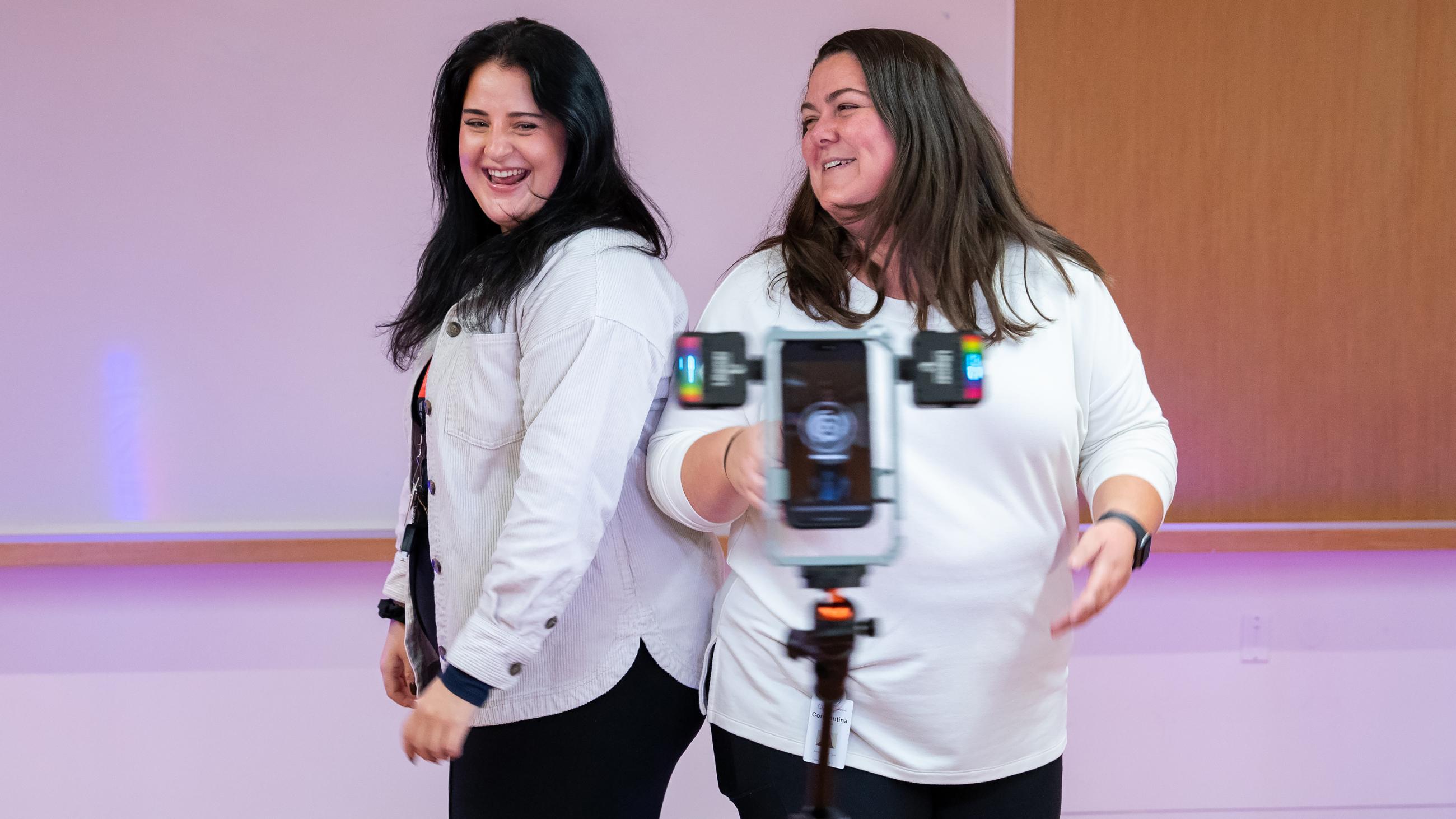 Two people smiling and posting together at the 360-degree video booth.