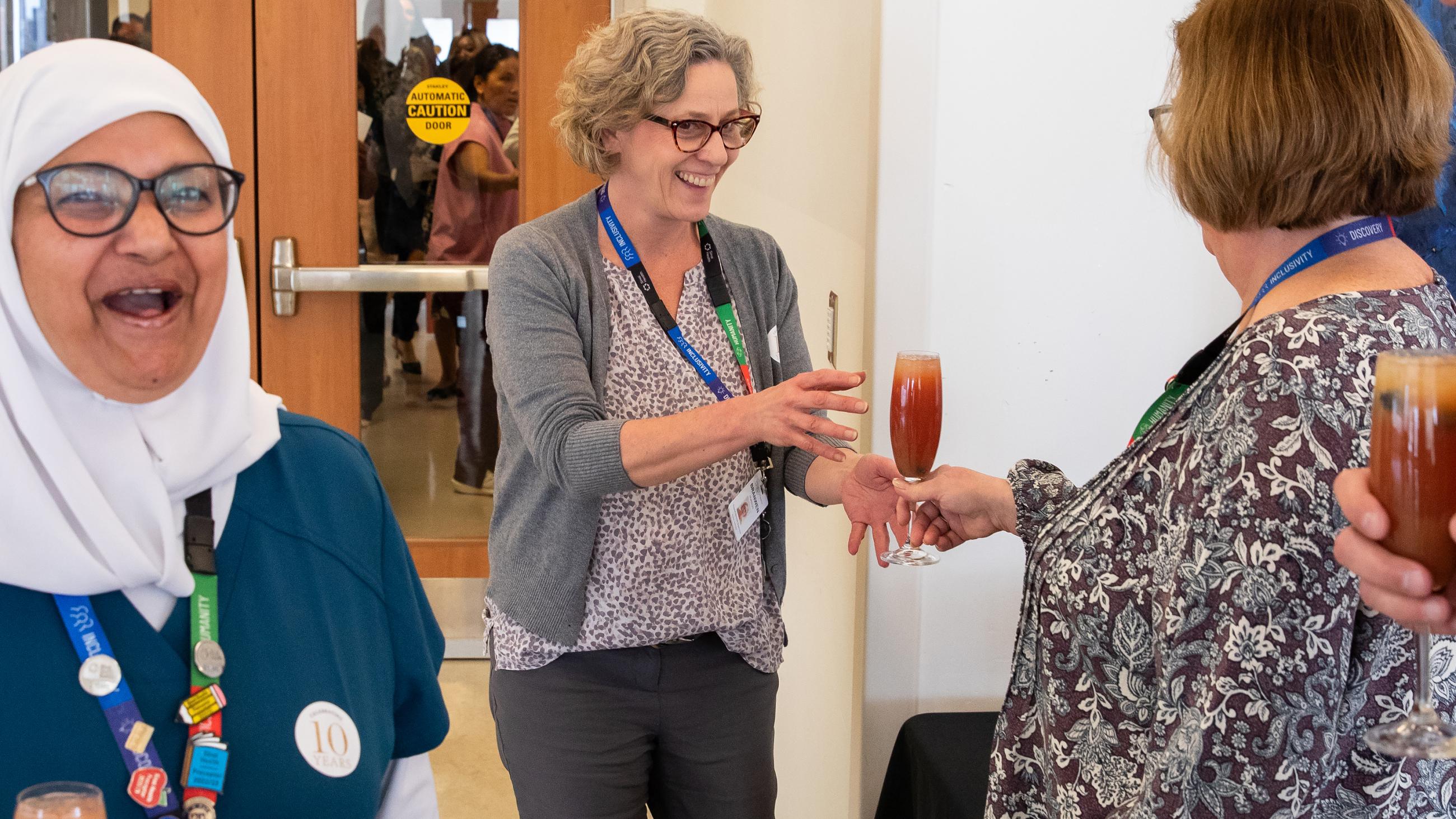 Service milestone recipients smiling as they receive a welcome beverage at the Service Celebration.