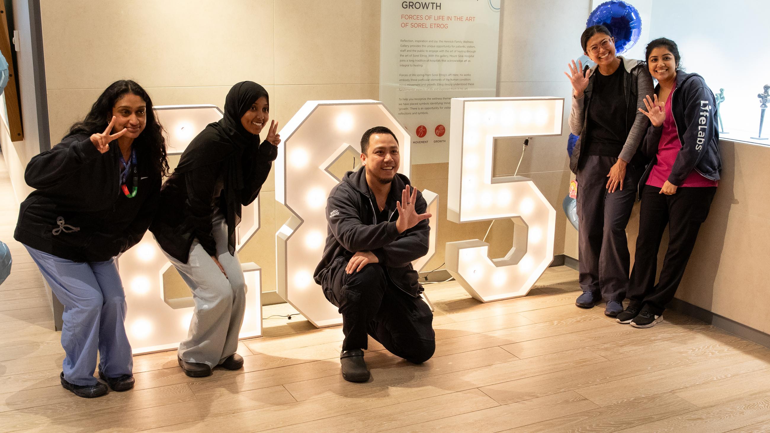 Service milestone recipients holding up two or five fingers to show the number of years they are celebrating.
