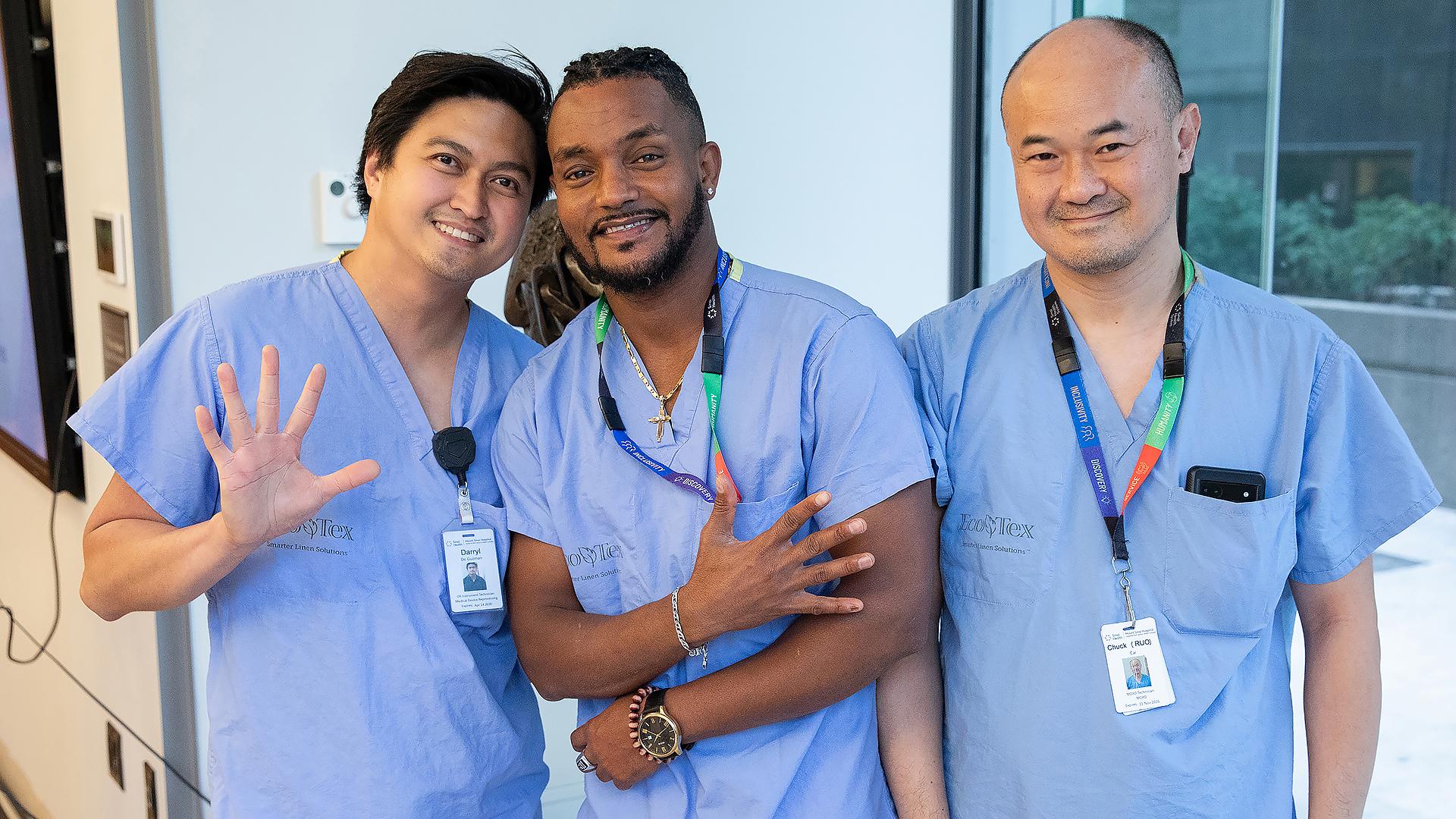 Service milestone recipients holding up five fingers to show the number of years they are celebrating.