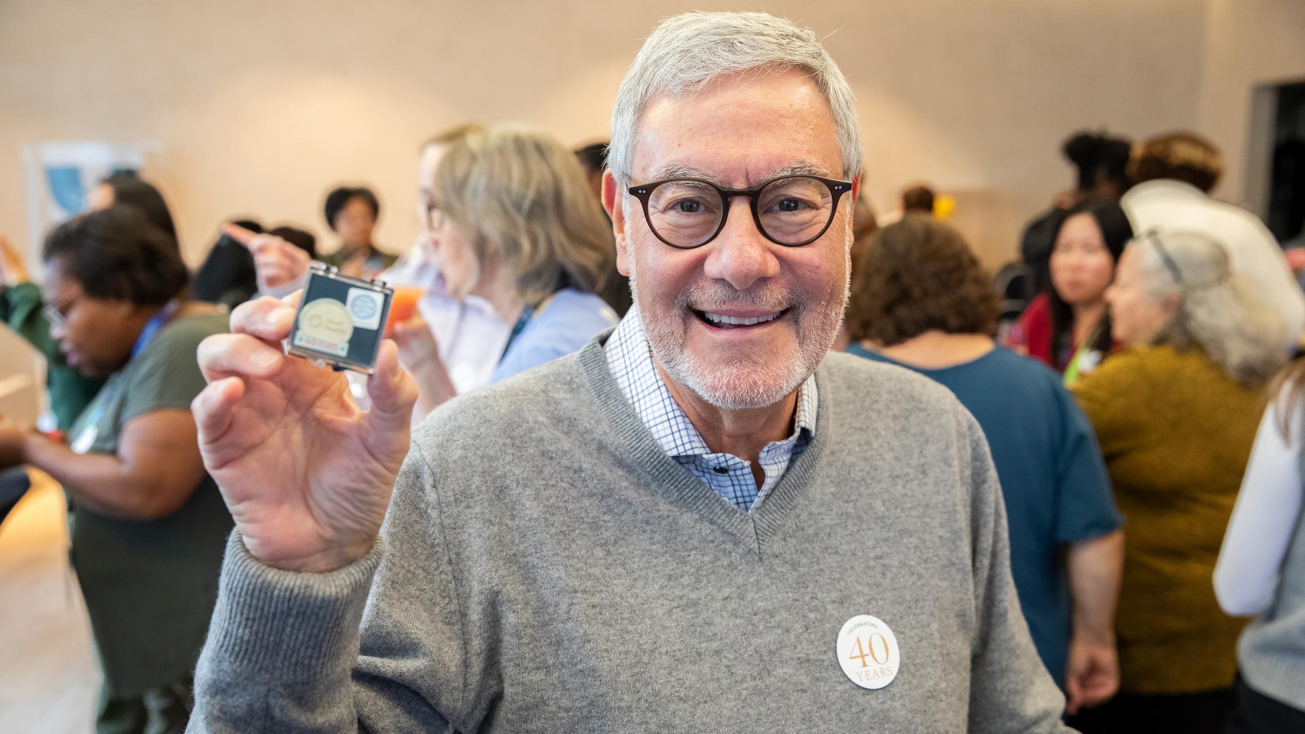 Service milestone recipient smiling while proudly holding up their 40-year service pin.